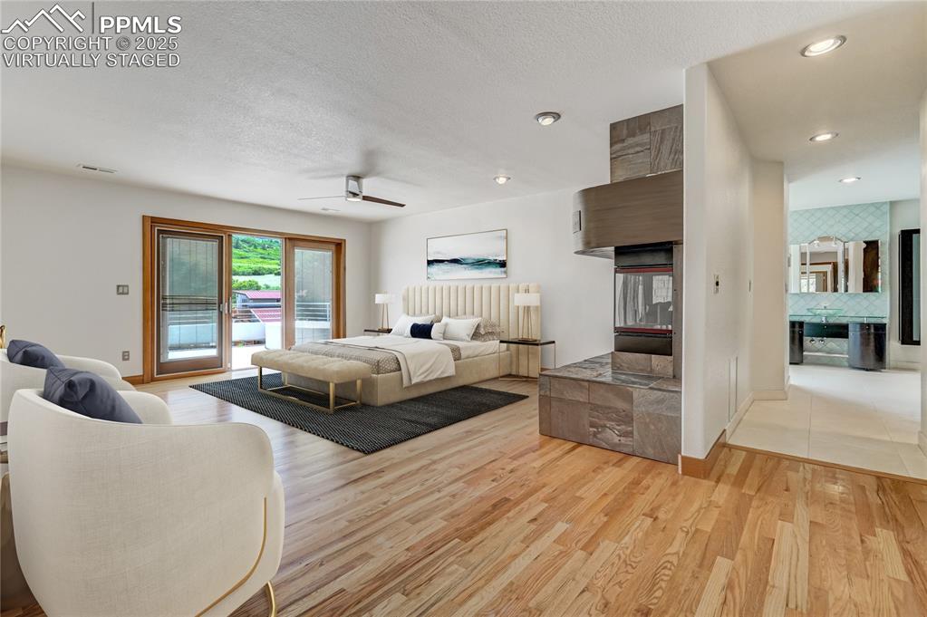 Bedroom featuring light wood-style flooring, access to outside, a ceiling fan, recessed lighting, and a textured ceiling, virtually staged