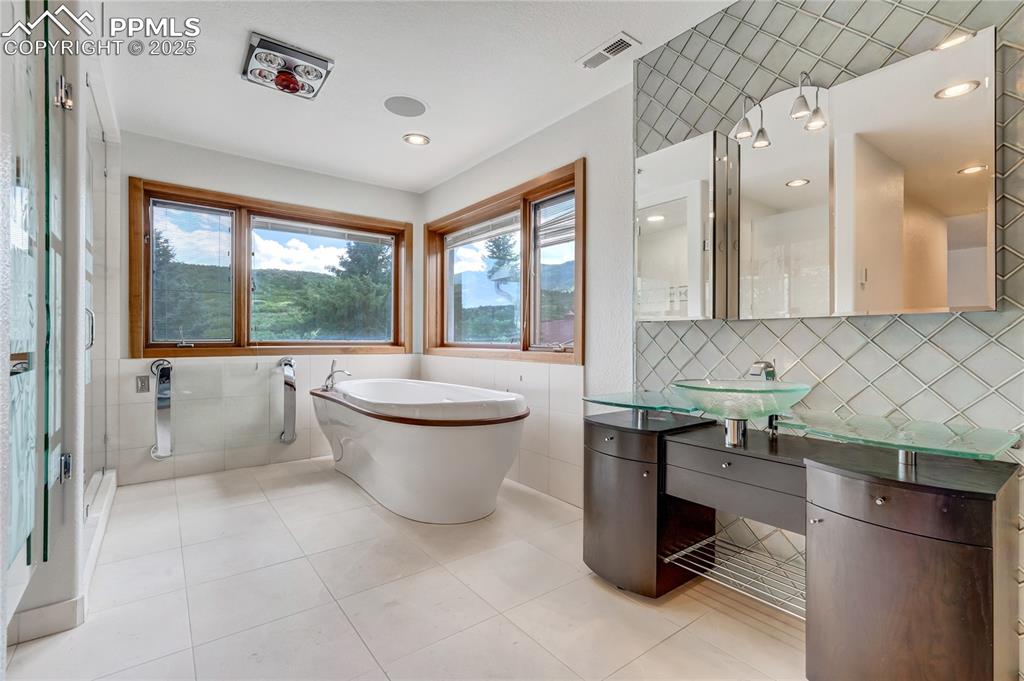 Bathroom with tile walls, decorative backsplash, vanity, a freestanding bath, and healthy amount of natural light