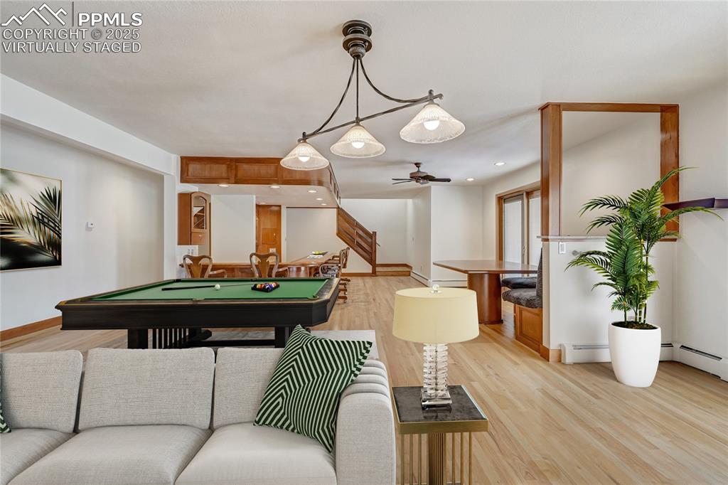 Playroom featuring light wood-style floors, billiards table, recessed lighting, and a baseboard heating unit, virtually staged