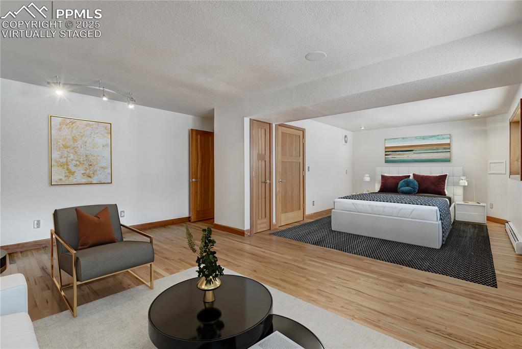 Bedroom featuring light wood-style floors and a textured ceiling, virtually staged