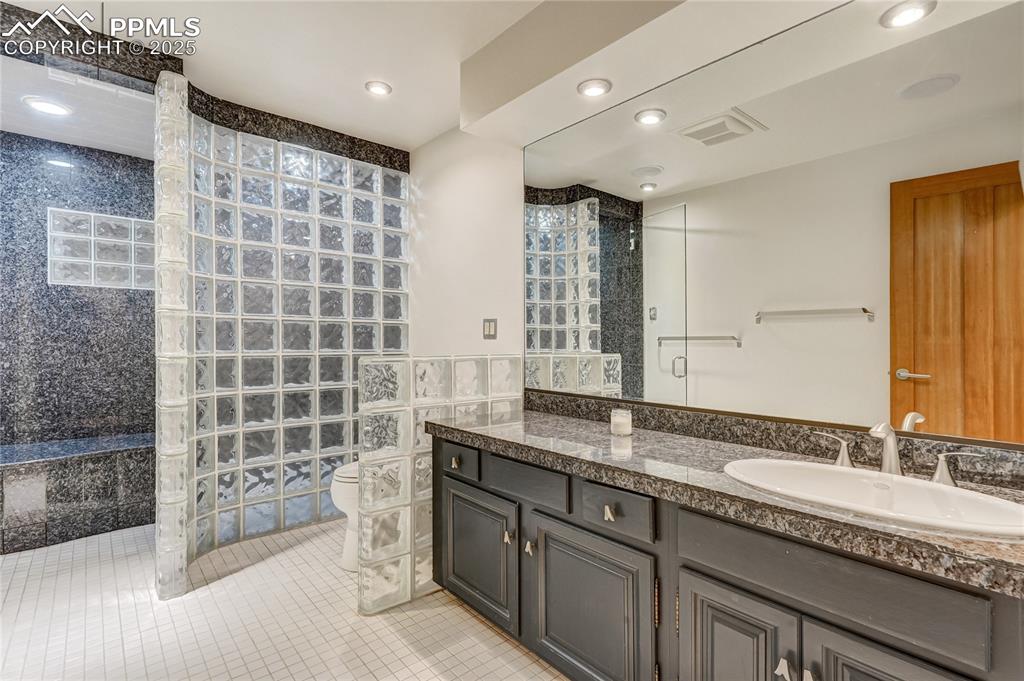 Full bathroom featuring walk in shower, vanity, light tile patterned flooring, recessed lighting, and tile walls