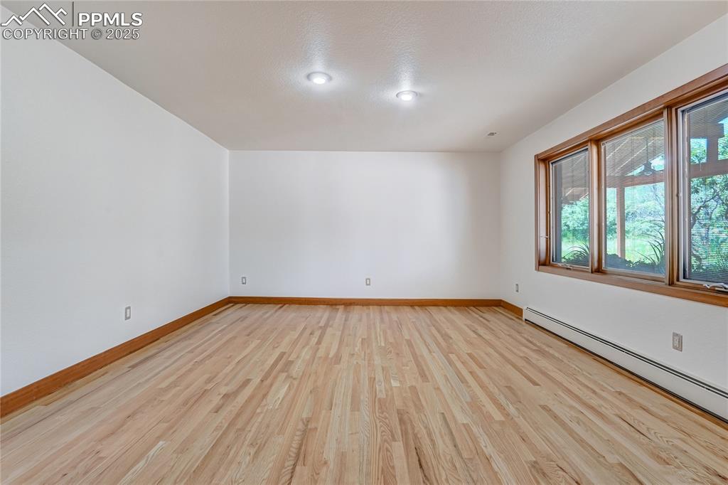 Empty room with light wood-style flooring and a baseboard heating unit