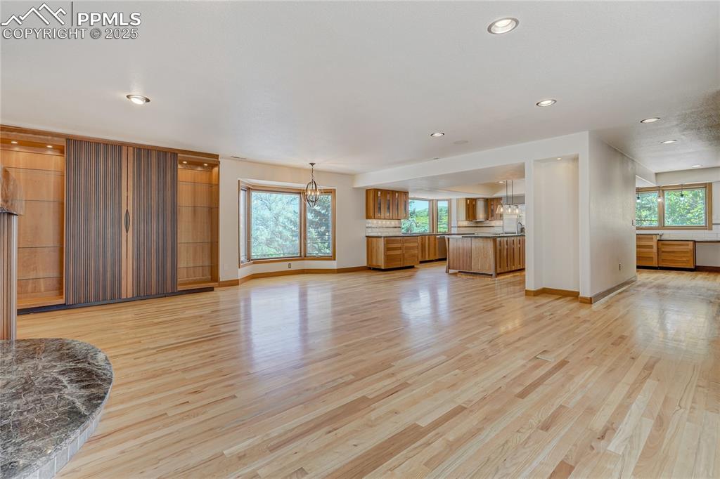 Unfurnished living room with light wood-style floors, healthy amount of natural light, recessed lighting, and a chandelier