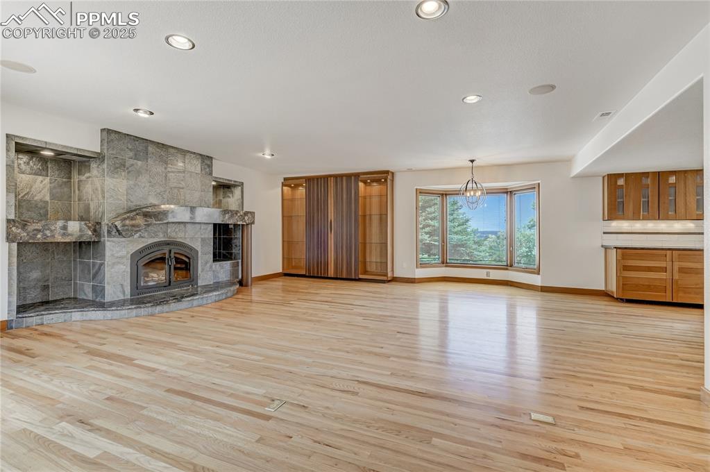 Unfurnished living room featuring a fireplace, light wood-type flooring, recessed lighting, and a chandelier