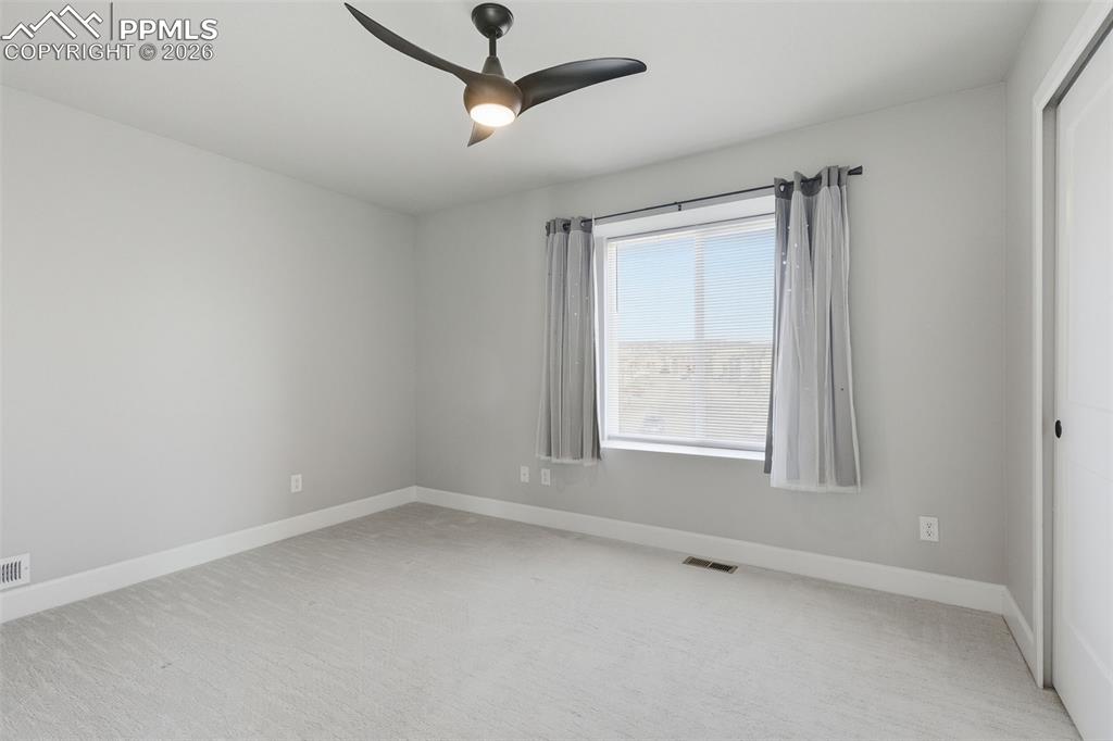 2nd spacious bedroom featuring light colored carpet and ceiling fan