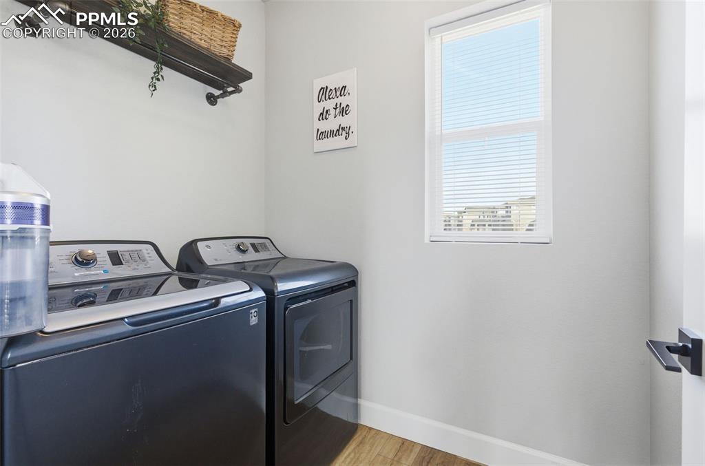 Laundry area with light wood finished floors and washer and clothes dryer