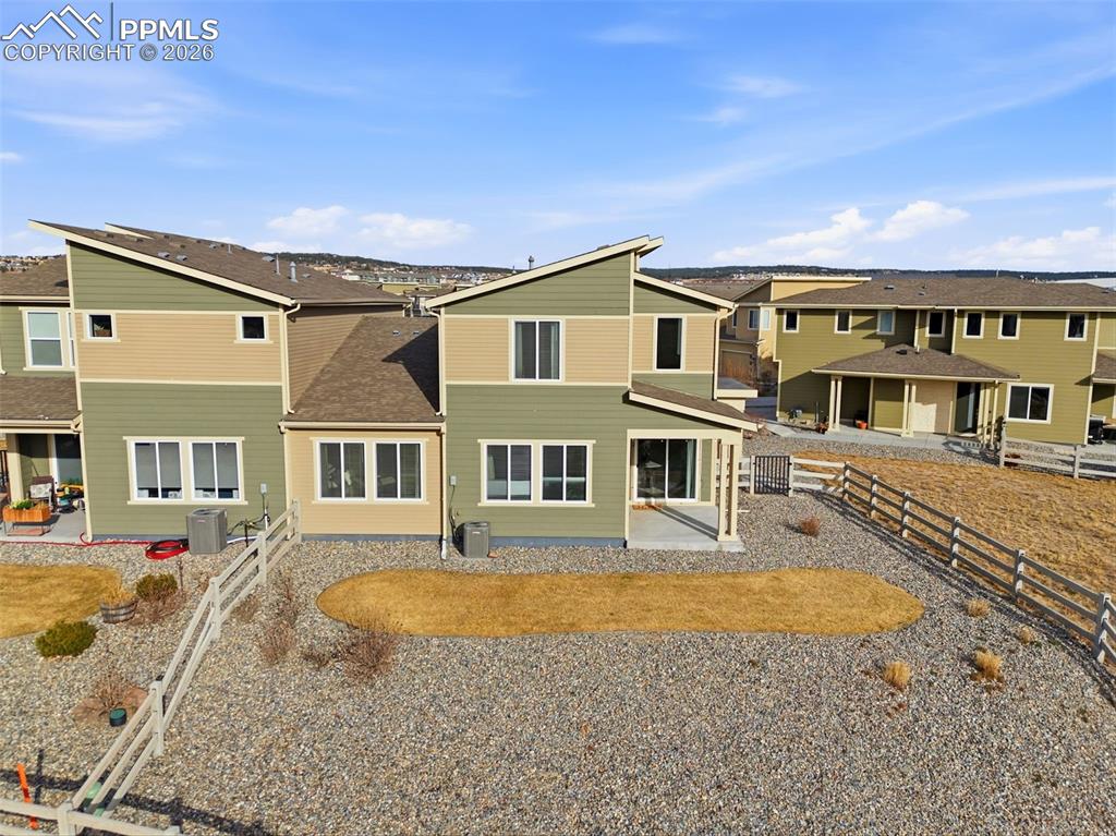 Rear view of house featuring a patio area, a residential view, a fenced backyard, and roof with shingles
