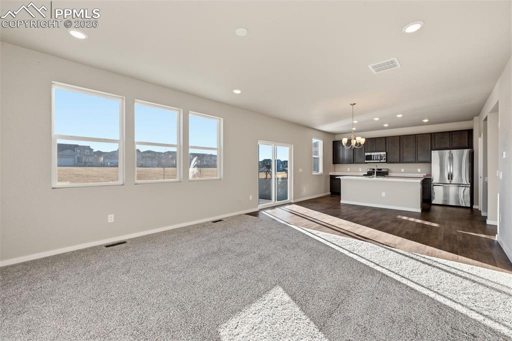 Unfurnished living room with a chandelier and dark colored carpet