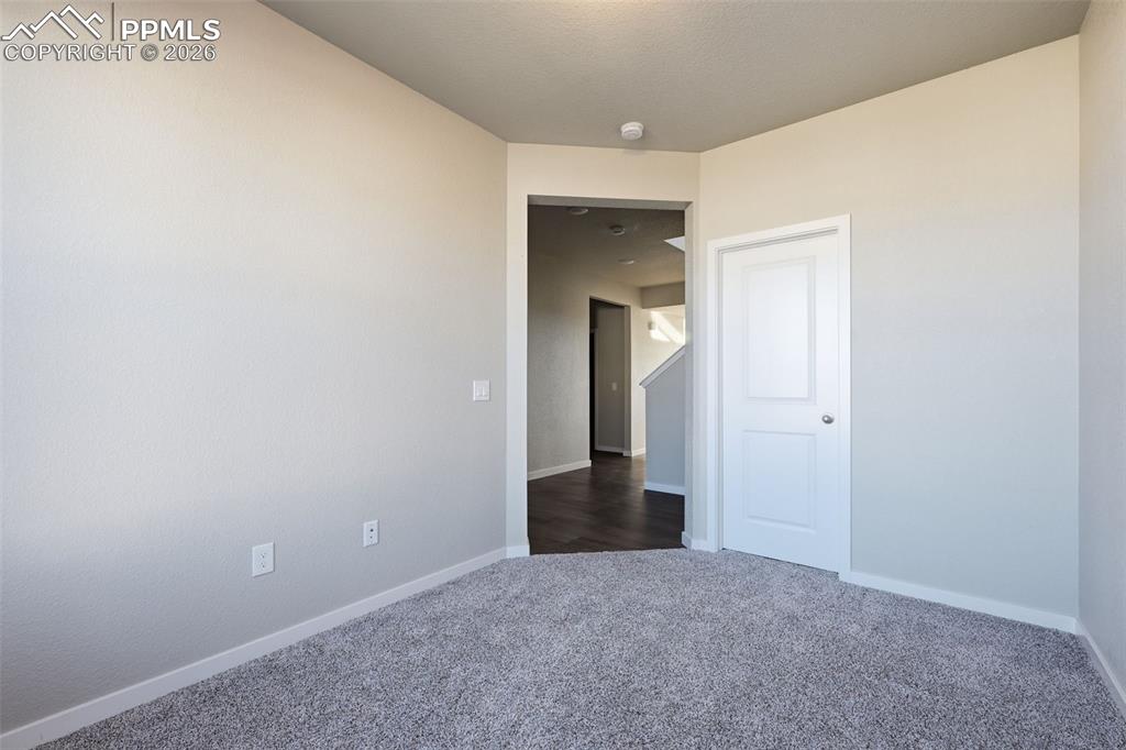 Unfurnished room featuring baseboards and dark colored carpet