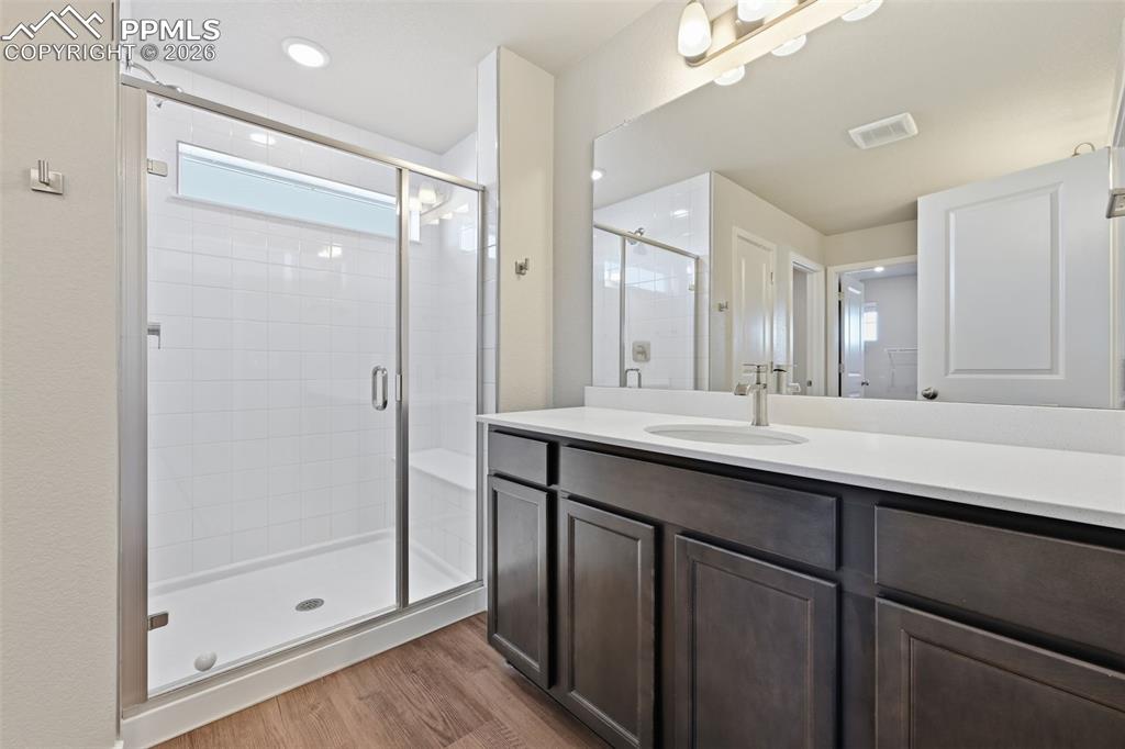 Bathroom featuring a stall shower, vanity, dark wood-style floors, and recessed lighting