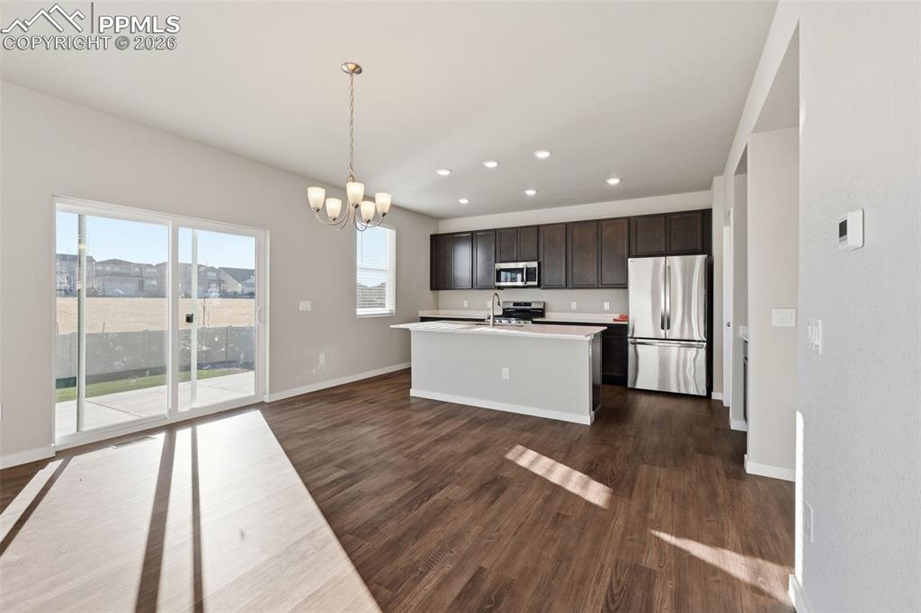 Kitchen with stainless steel appliances, light countertops, a chandelier, dark wood finished floors, and dark wood finish cabinetry