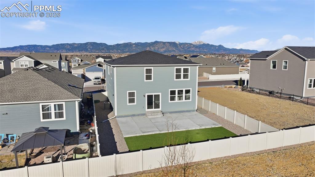 Rear view of property featuring a residential view, a fenced backyard, a patio, and a mountain view