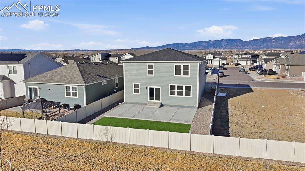 Rear view of property with a residential view, a fenced backyard, and a mountain view