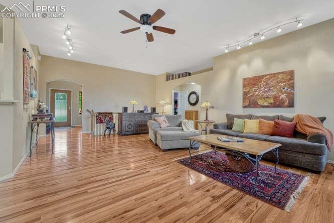 Living room featuring arched walkways, light wood-style flooring, and ceiling fan
