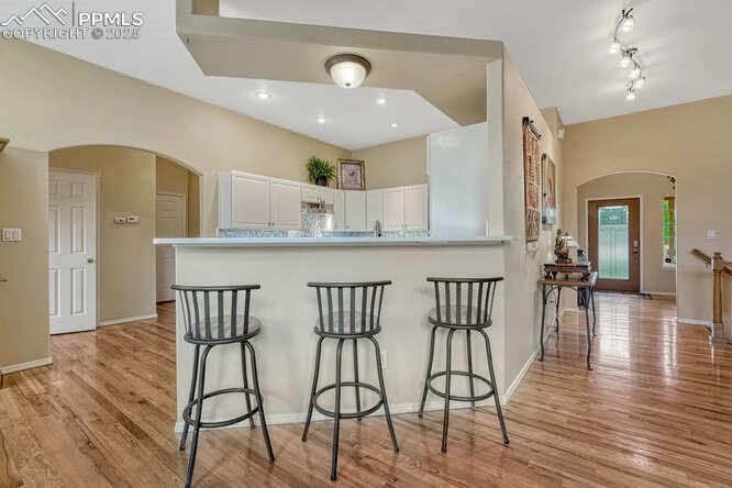 Kitchen with arched walkways, white cabinetry, a kitchen breakfast bar 