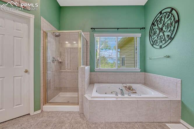 Bathroom featuring a stall shower, a bath, and dual vanities