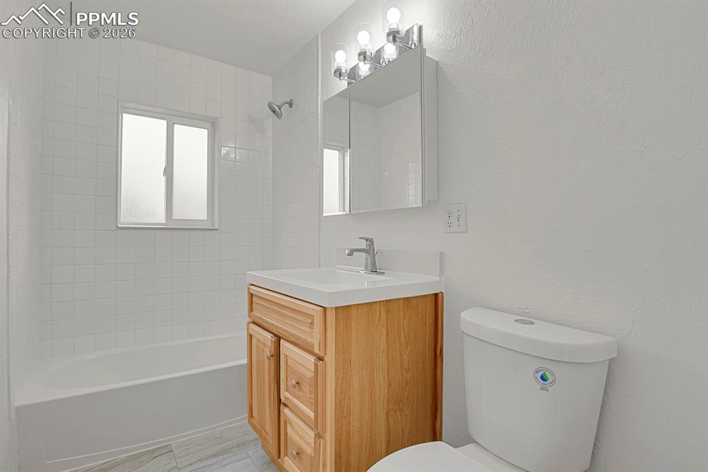 Renovated bathroom with new tile flooring, lighting, vanity, and plumbing fixtures