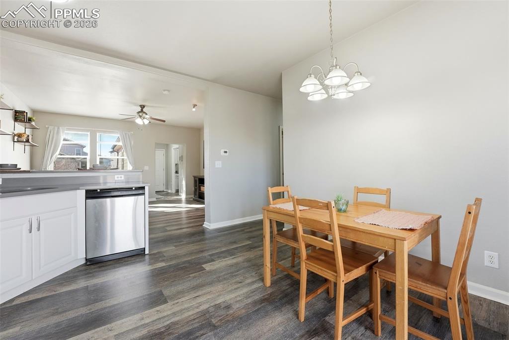Dining space with a ceiling fan, dark wood finished floors, and a chandelier