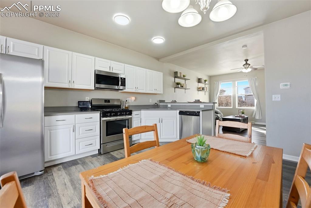 Kitchen featuring stainless steel appliances, white cabinets, light wood finished floors, and a peninsula