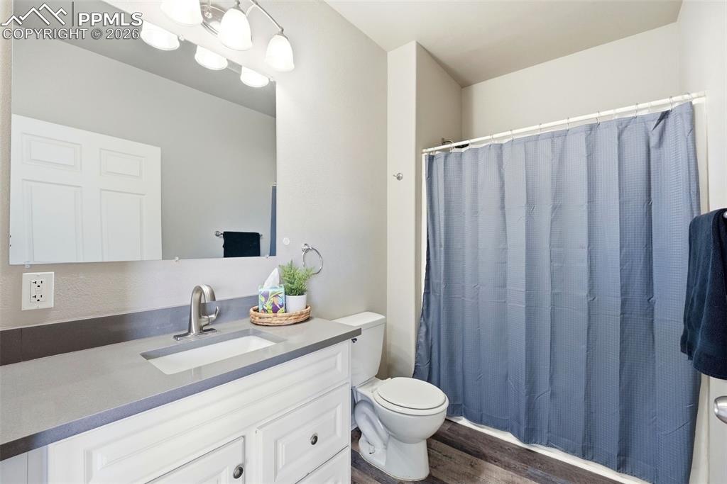 Bathroom with vanity, a shower with shower curtain, and dark wood finished floors
