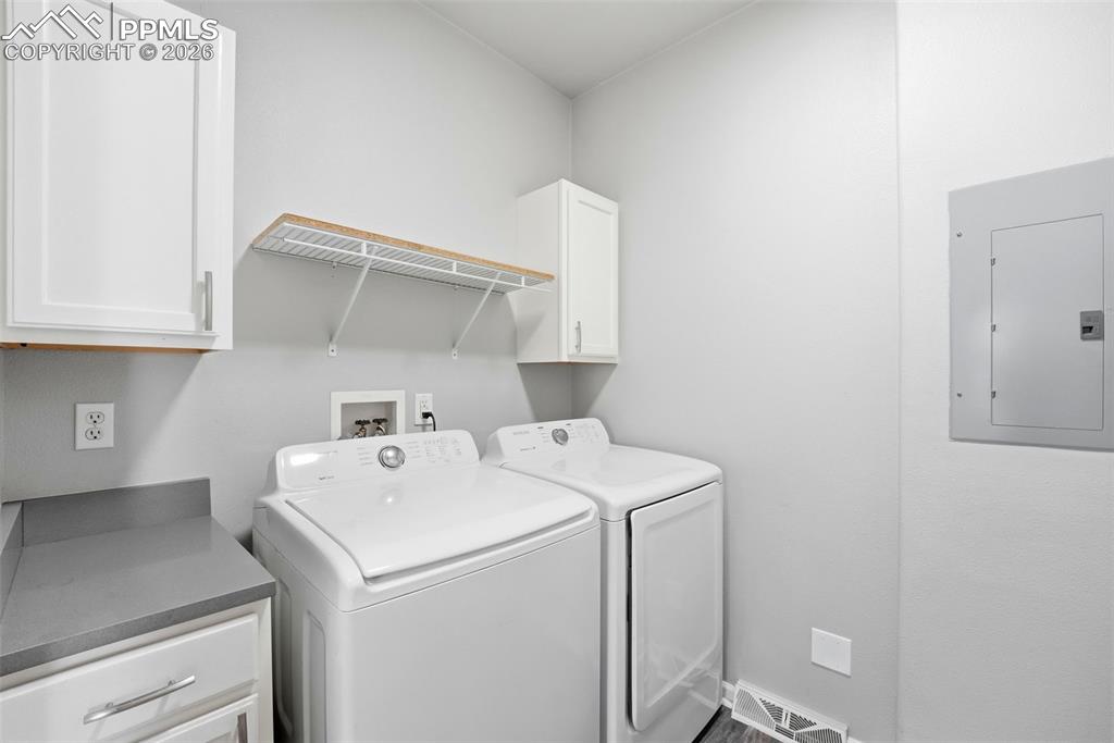 Laundry area with cabinet space, electric panel, and washing machine and dryer