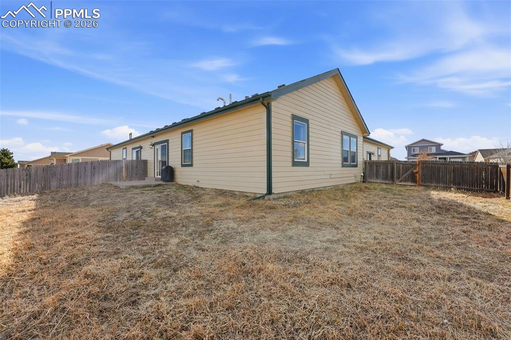 Rear view of house featuring a fenced backyard and a patio