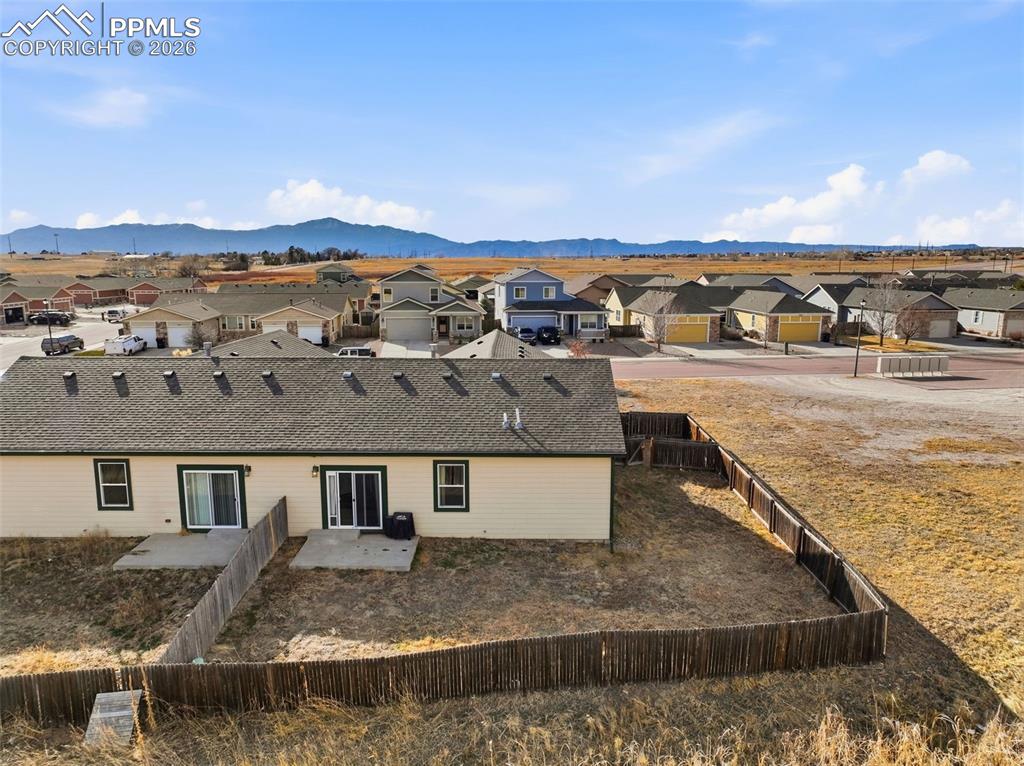 Rear view of property featuring a residential view, a mountain view, a fenced backyard, and a patio