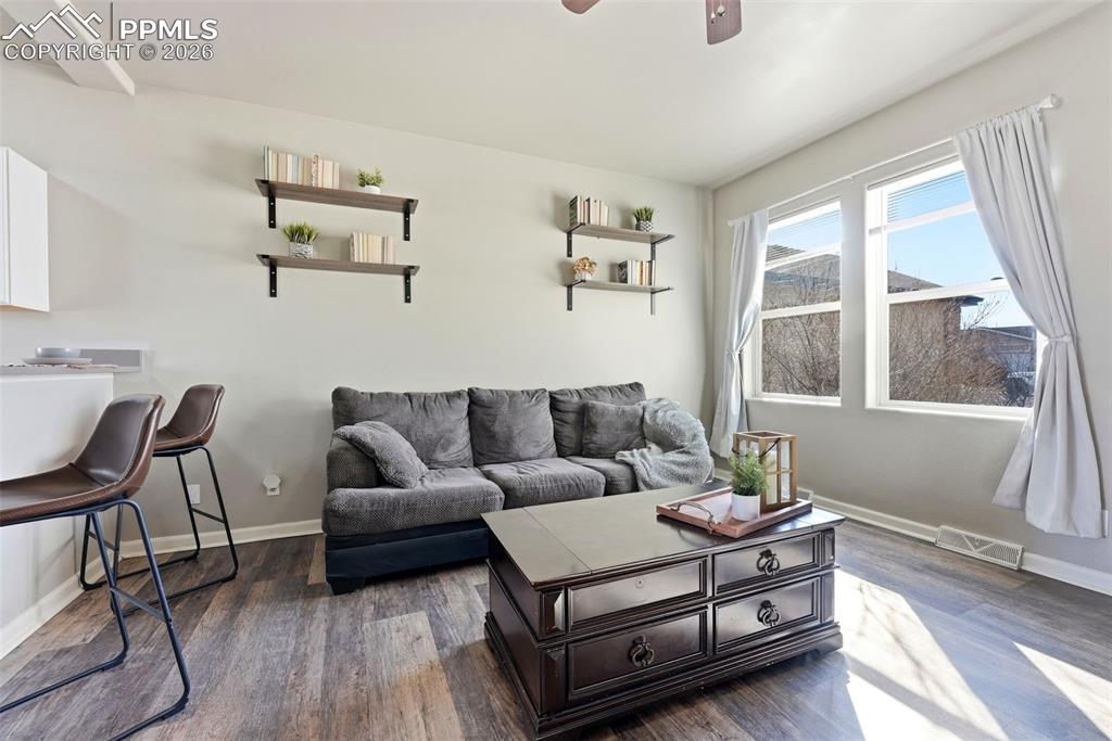 Living area featuring ceiling fan and dark wood-style floors