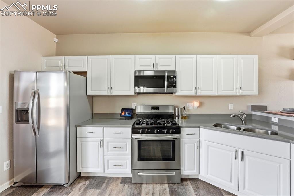 Kitchen featuring stainless steel appliances, white cabinets, and light wood finished floors