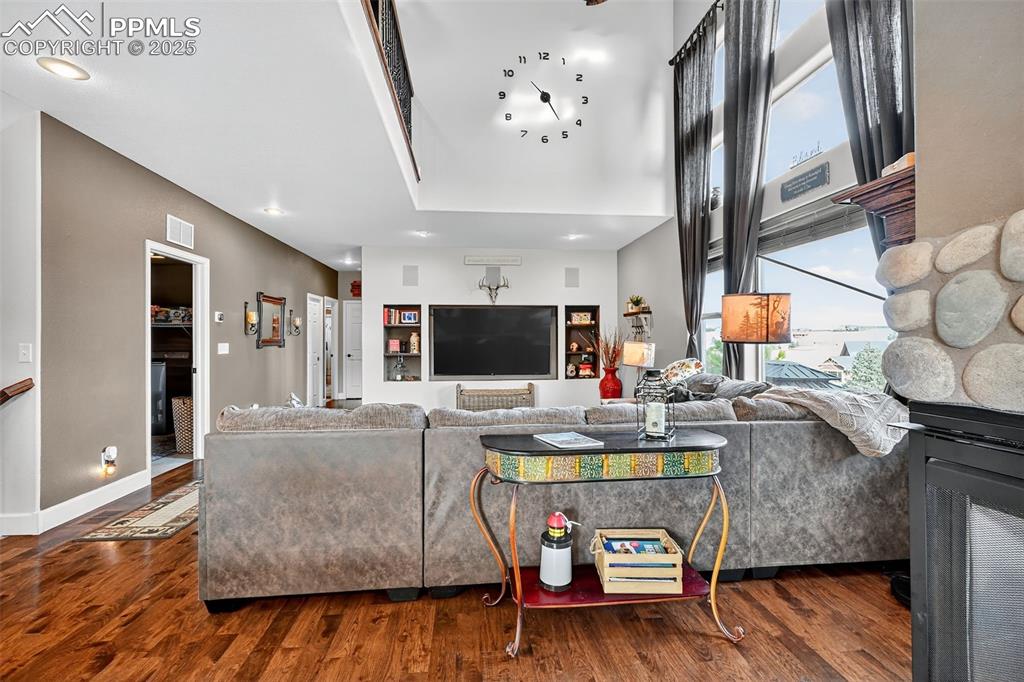 Living area with a fireplace, dark wood-type flooring, a high ceiling, and recessed lighting