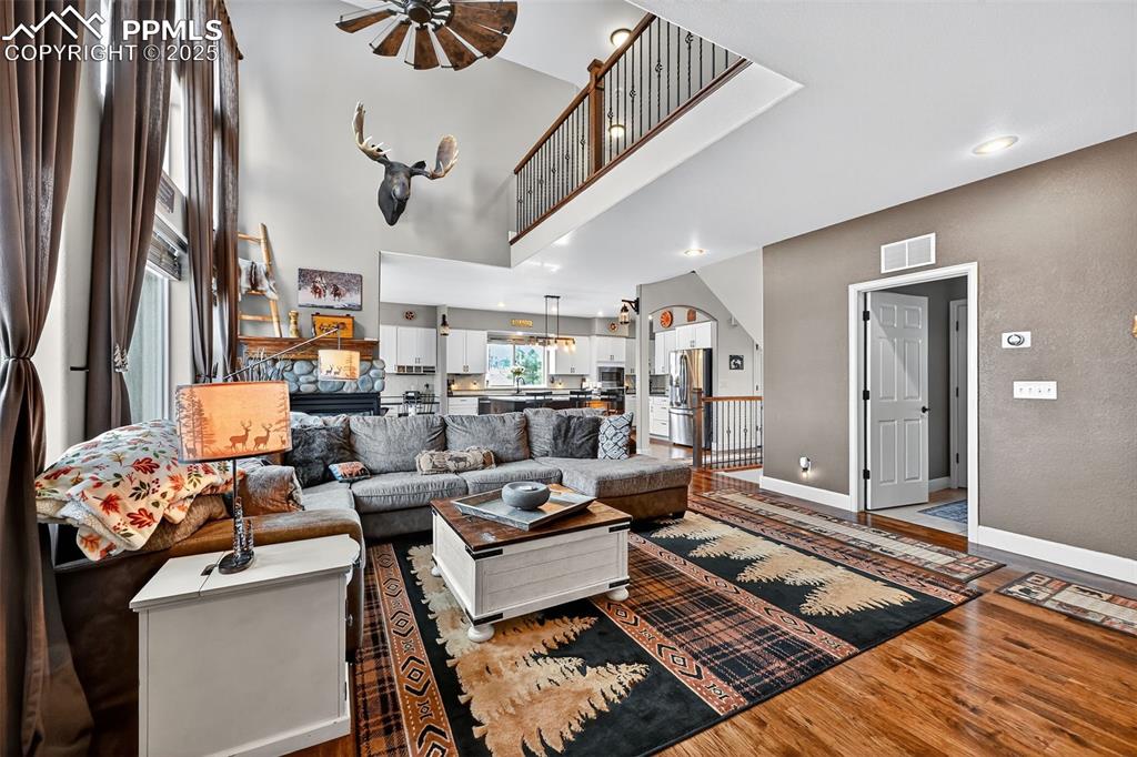 Living room featuring wood finished floors, a ceiling fan, and a towering ceiling