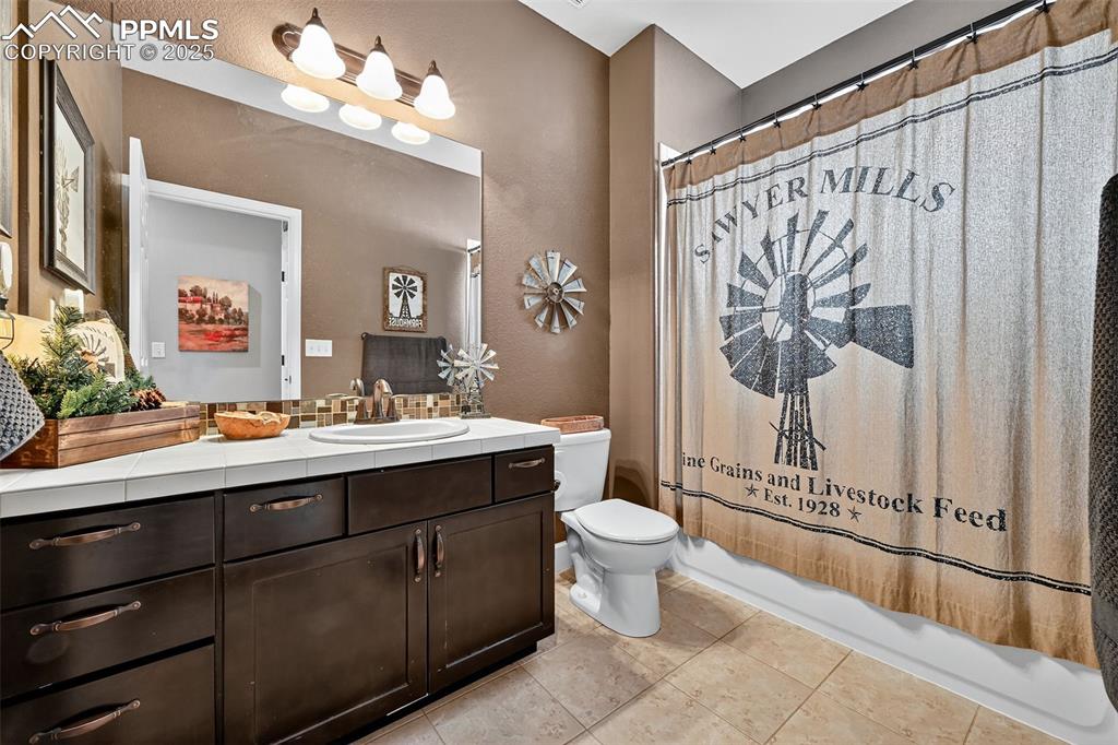Bathroom featuring vanity, light tile patterned flooring, shower / bath combo, and a textured wall
