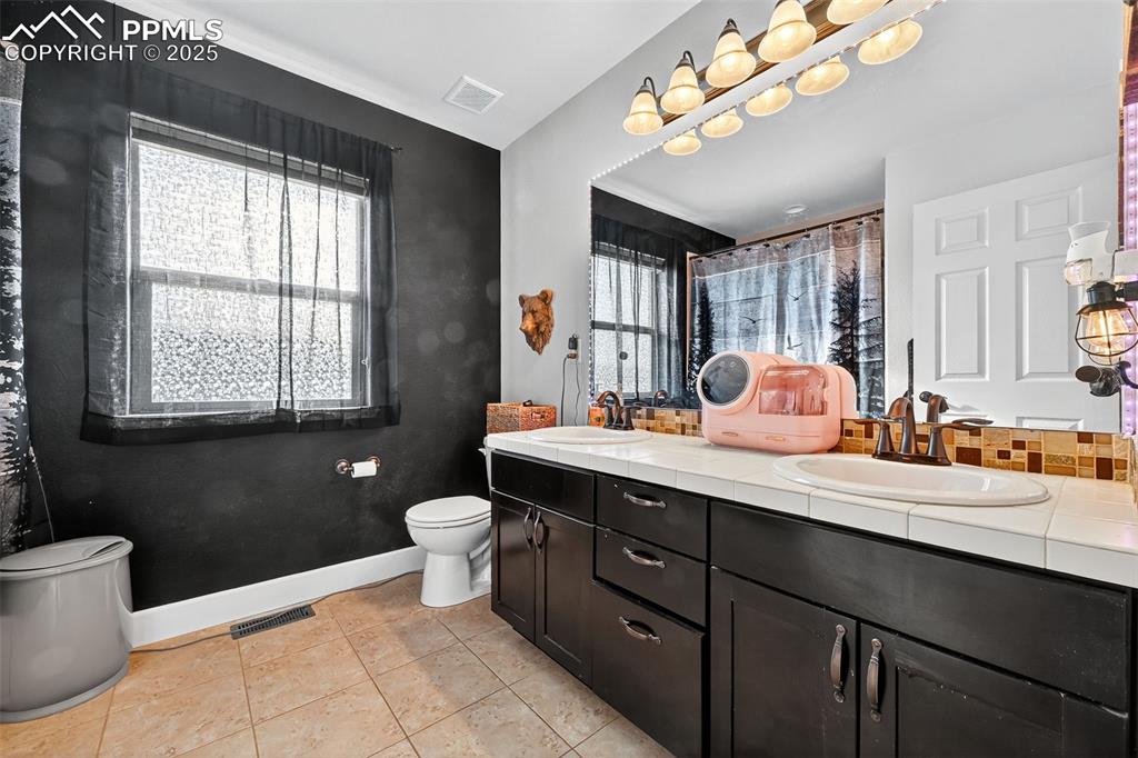 Bathroom featuring double vanity, a shower with shower curtain, and light tile patterned flooring