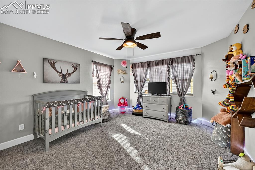 Bedroom featuring a crib, carpet, and ceiling fan