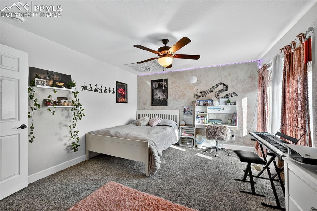Carpeted bedroom featuring baseboards and ceiling fan