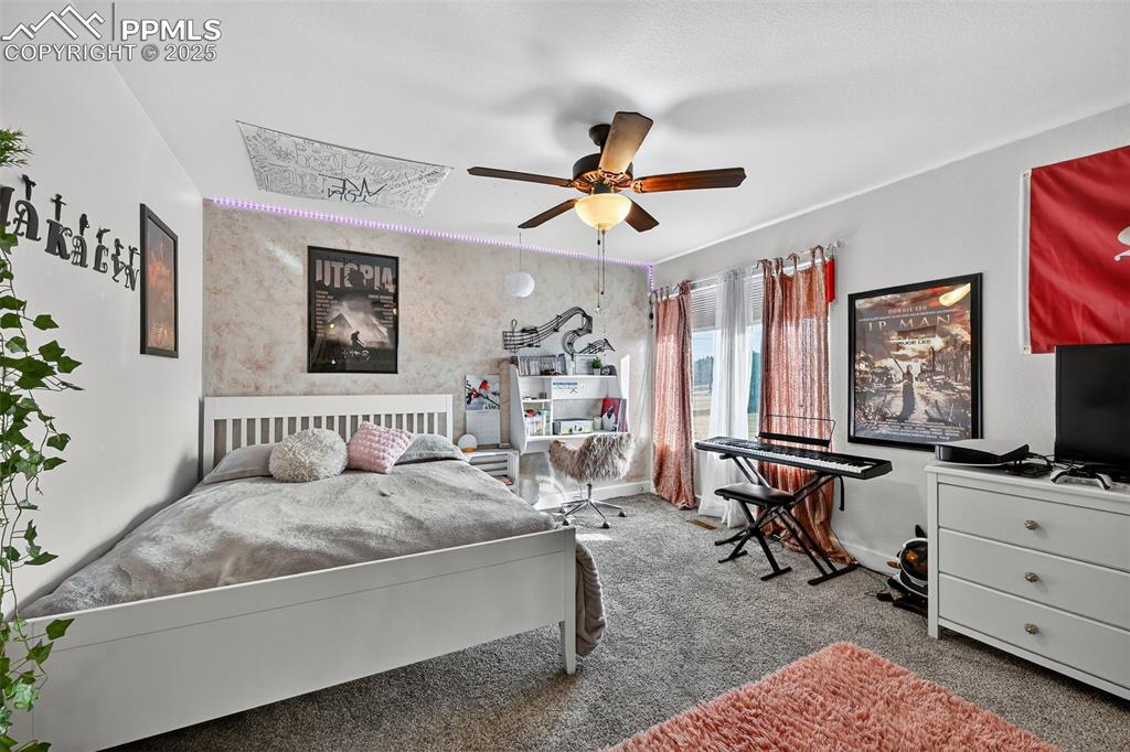 Carpeted bedroom featuring baseboards and ceiling fan