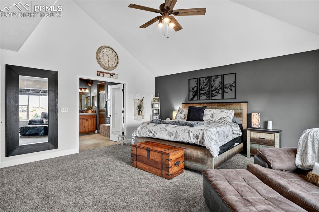 Bedroom with high vaulted ceiling, carpet flooring, ensuite bathroom, and ceiling fan