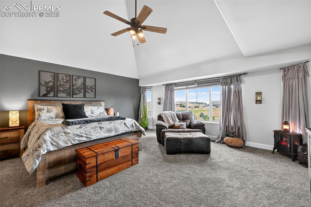 Carpeted bedroom featuring ceiling fan and high vaulted ceiling