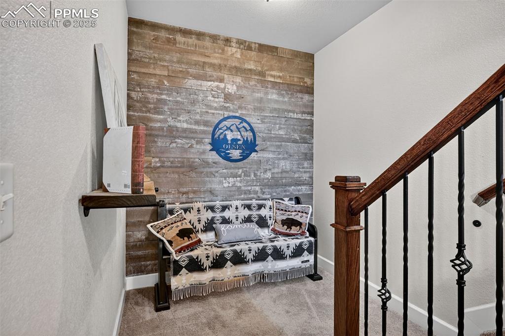Stairway featuring wooden walls, a textured wall, and carpet floors