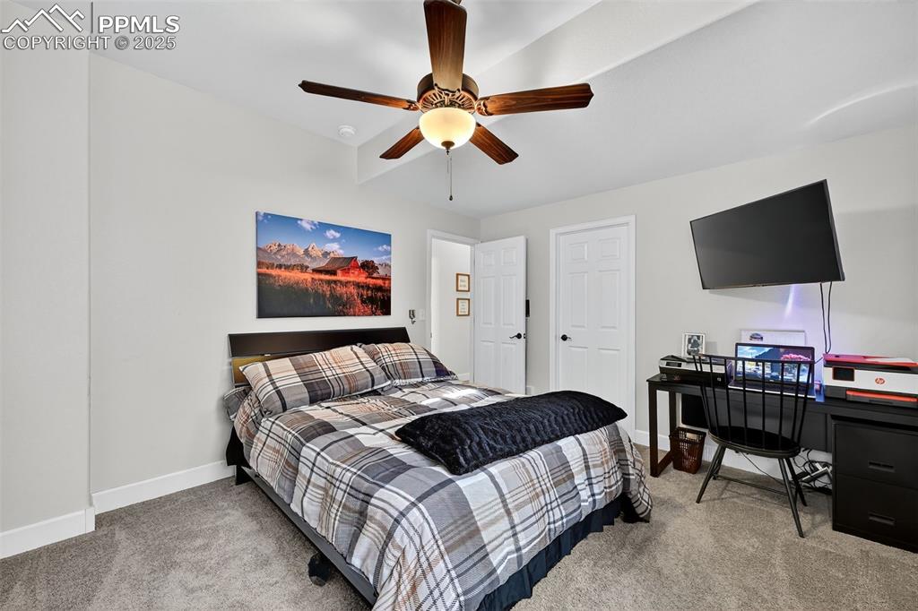 Bedroom featuring light colored carpet, a ceiling fan, and a desk