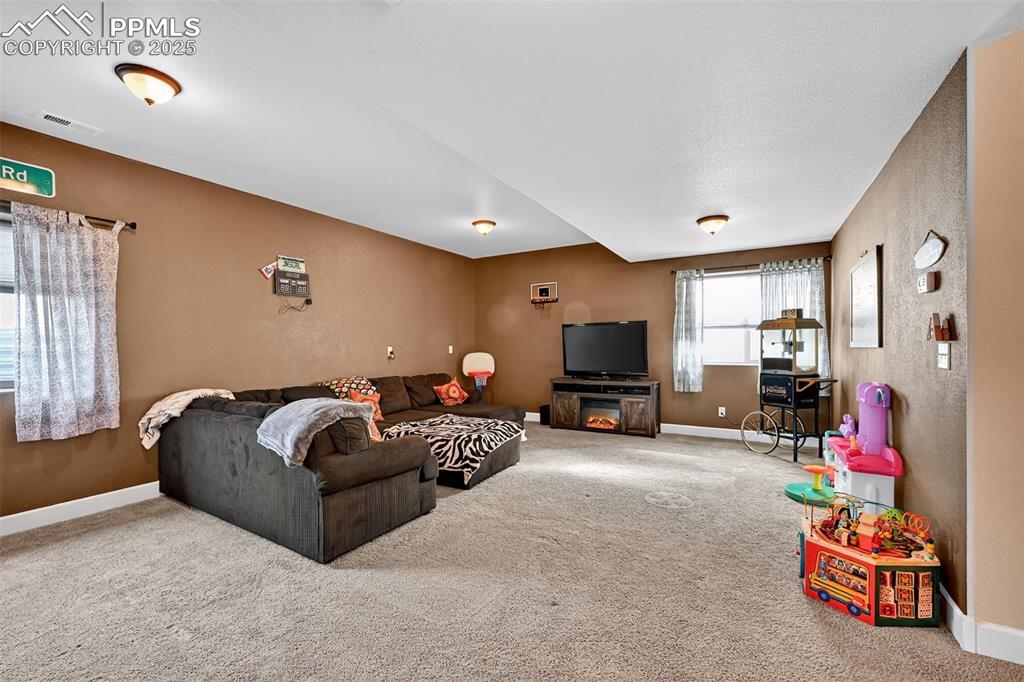 Carpeted living room with baseboards and a textured wall