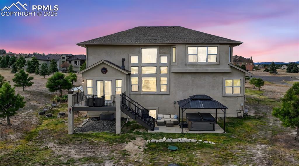 Back of house with a hot tub, stairway, a patio area, stucco siding, and roof with shingles