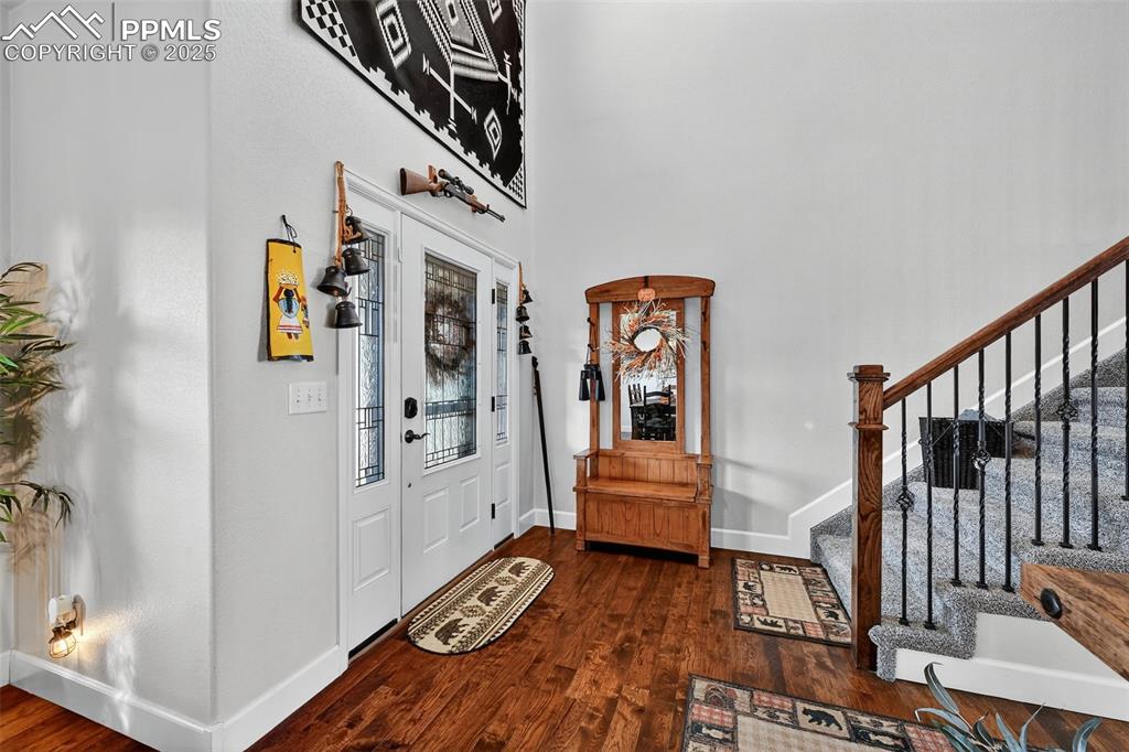 Foyer featuring dark wood-type flooring, stairs, and a high ceiling