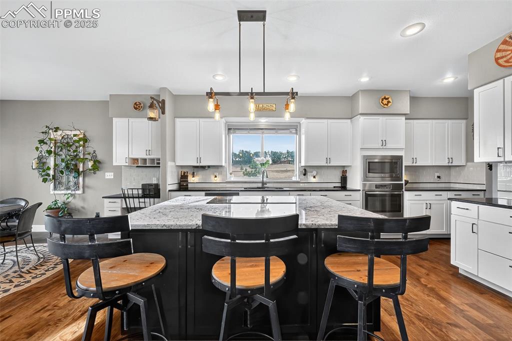 Kitchen featuring dark cabinetry, a kitchen breakfast bar, dark wood-type flooring, and recessed lighting