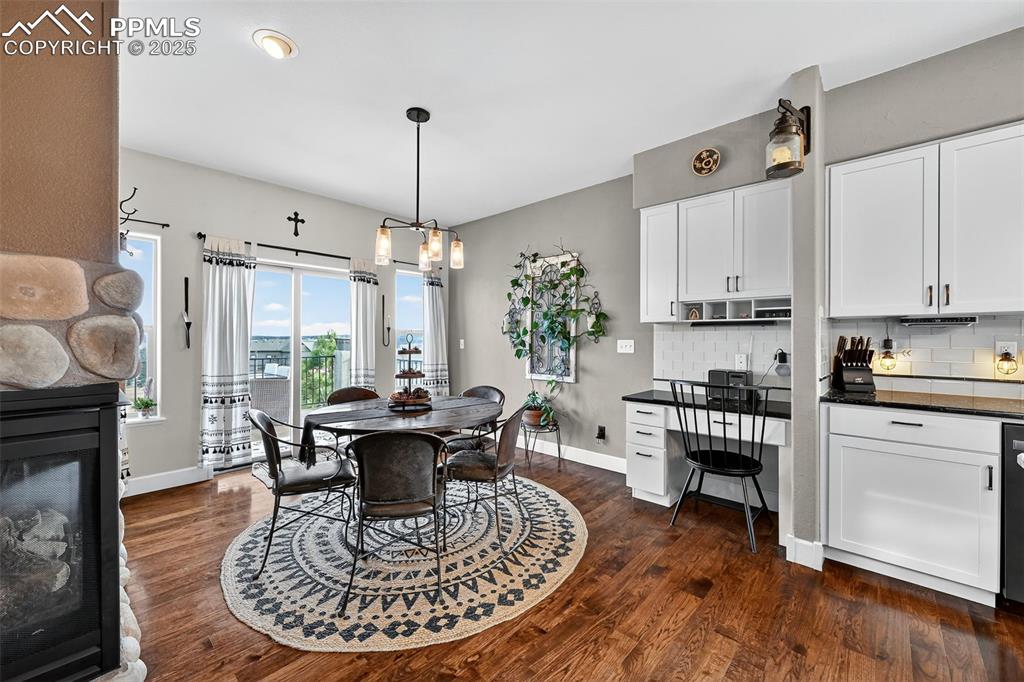 Dining room featuring dark wood-style flooring, a fireplace, built in study area, a chandelier, and recessed lighting