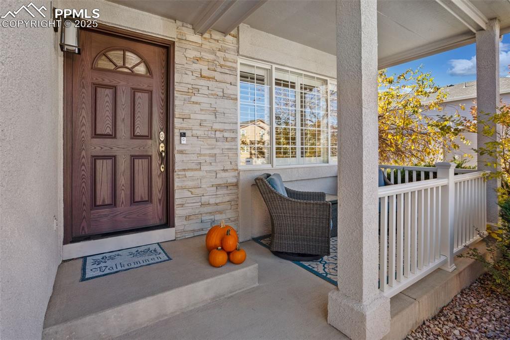 Doorway to property with stone siding and a porch