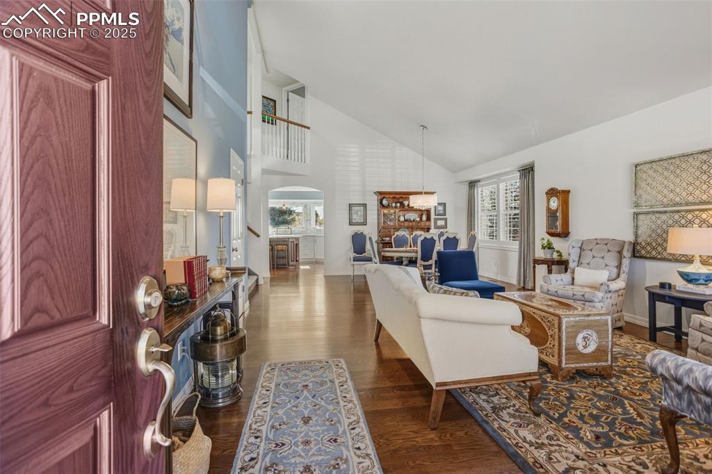 Living area featuring dark wood-style flooring, high vaulted ceiling, and arched walkways