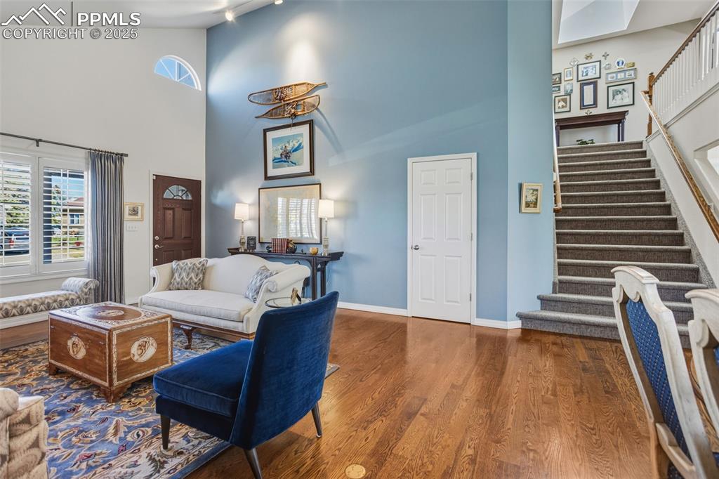 Living area with high vaulted ceiling, wood finished floors, and stairway