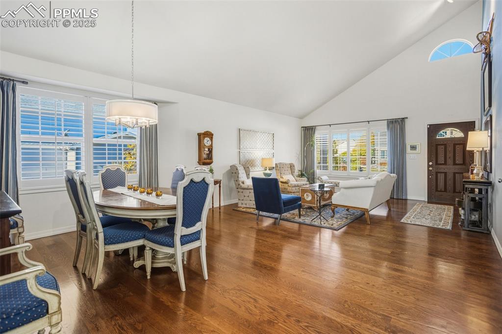 Dining area with high vaulted ceiling and dark wood-type flooring