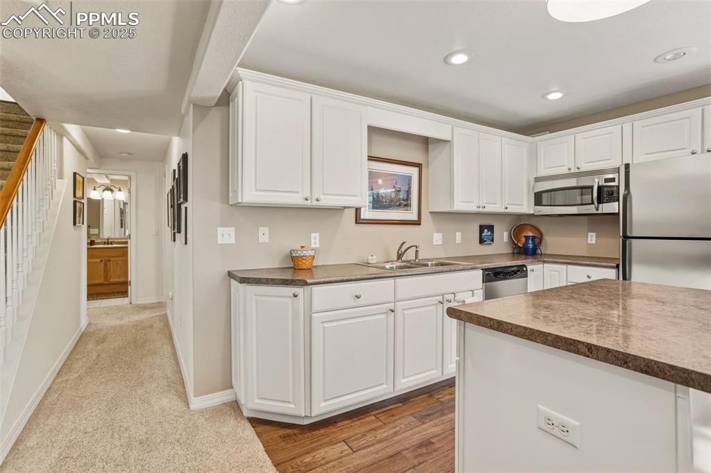 Kitchen with stainless steel appliances, white cabinets, dark countertops, and recessed lighting